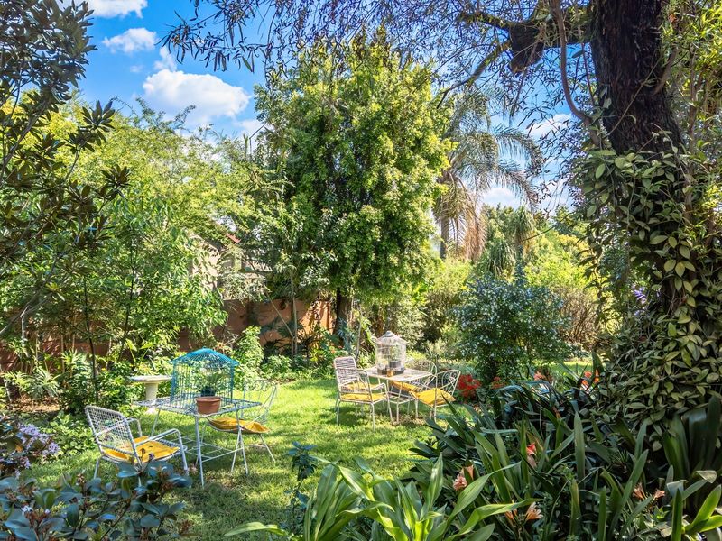 A lush, well-maintained private garden featuring mature trees, established greenery, and a peaceful outdoor setting.