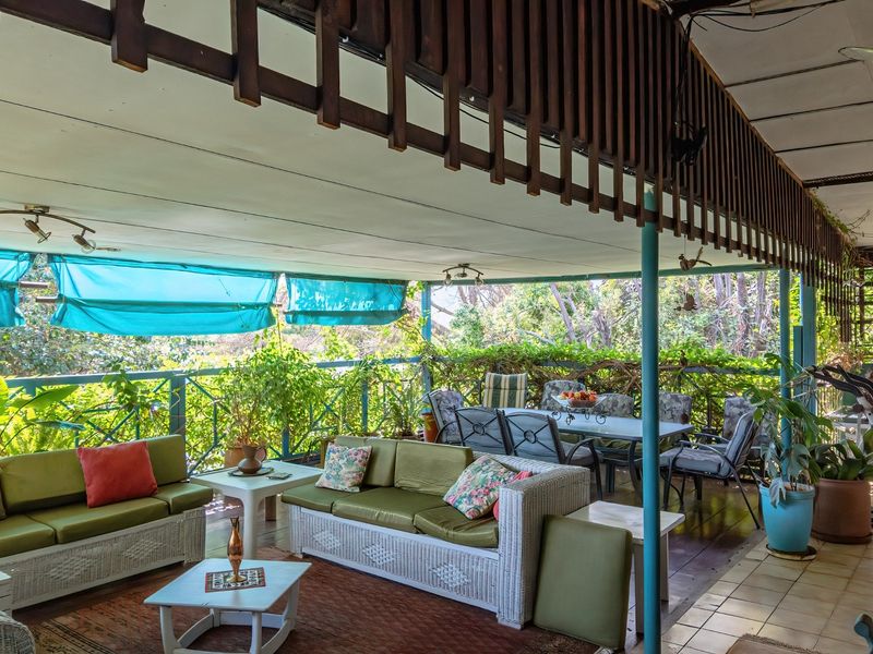 Spacious covered patio featuring timber decking, metal balustrades, and a slatted timber roof screen, offering a relaxed outdoor living and dining area.