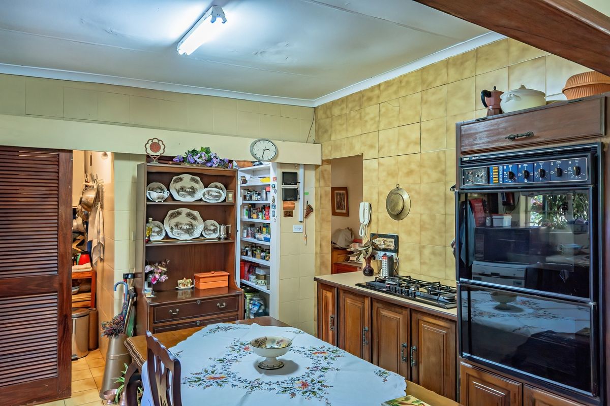 A dated kitchen featuring traditional wooden cabinetry, built-in oven, gas hob, and tiled wall finishes, offering significant potential for a modern renovation.