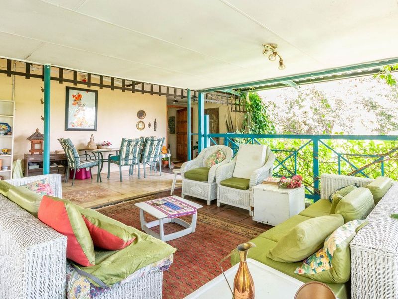 A spacious covered patio area featuring tiled flooring and a railing, offering a versatile outdoor living space suitable for relaxation and entertaining.