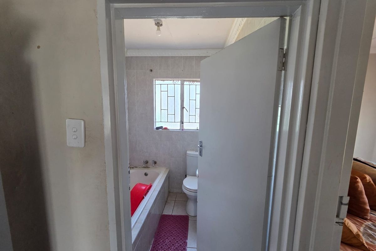 A functional bathroom featuring a built-in bathtub, toilet, and tiled finishes, requiring cosmetic updates to improve its overall condition and aesthetic appeal.