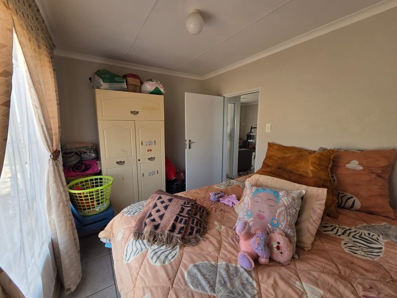 A functional bedroom featuring tiled flooring and a built-in cupboard, offering a neutral base for potential interior updates.