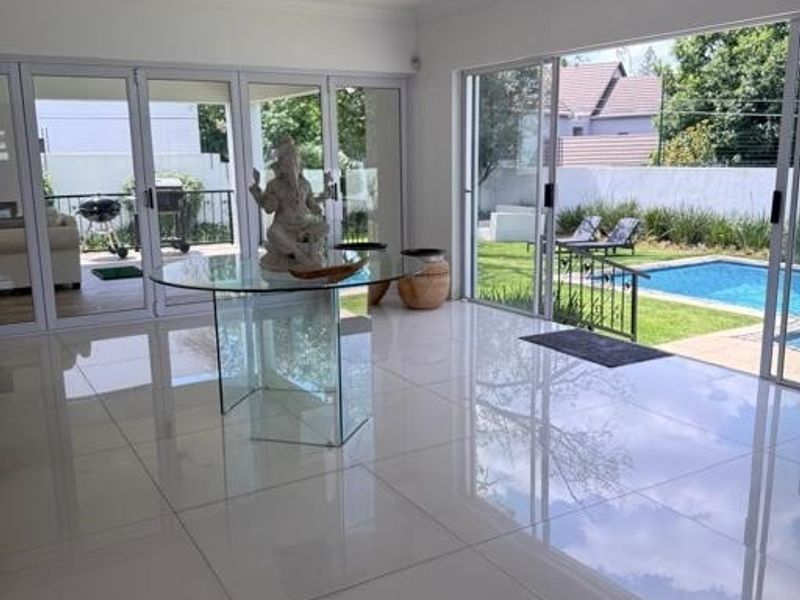 Spacious living area featuring large format polished floor tiles and expansive aluminium stacker doors providing seamless indoor-outdoor flow to the pool area.