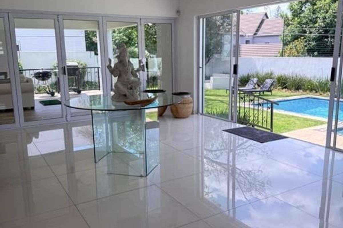 Spacious living area featuring large format polished floor tiles and expansive aluminium stacker doors providing seamless indoor-outdoor flow to the pool area.