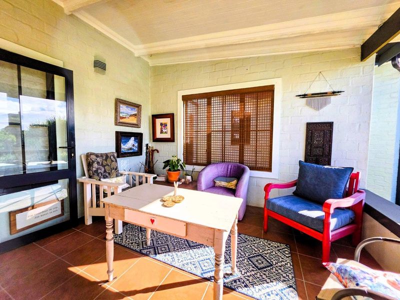 A bright, enclosed patio area featuring tiled flooring, painted brick walls, and an exposed beam ceiling, providing a cozy and inviting space.