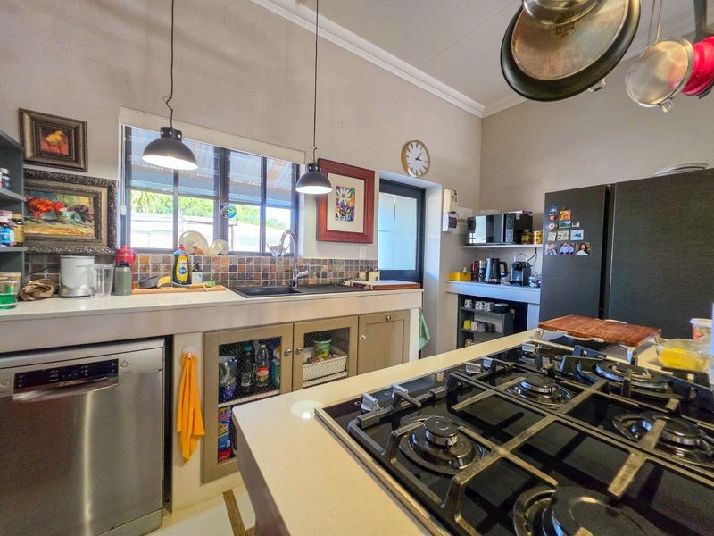A functional kitchen featuring stone countertops, a gas hob, tiled backsplash, and built-in cabinetry with ample storage space.