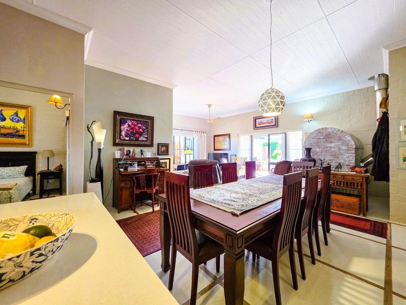 Spacious open-plan living and dining area featuring a brick fireplace, coved ceilings, and direct access to the outdoor patio through sliding glass doors.