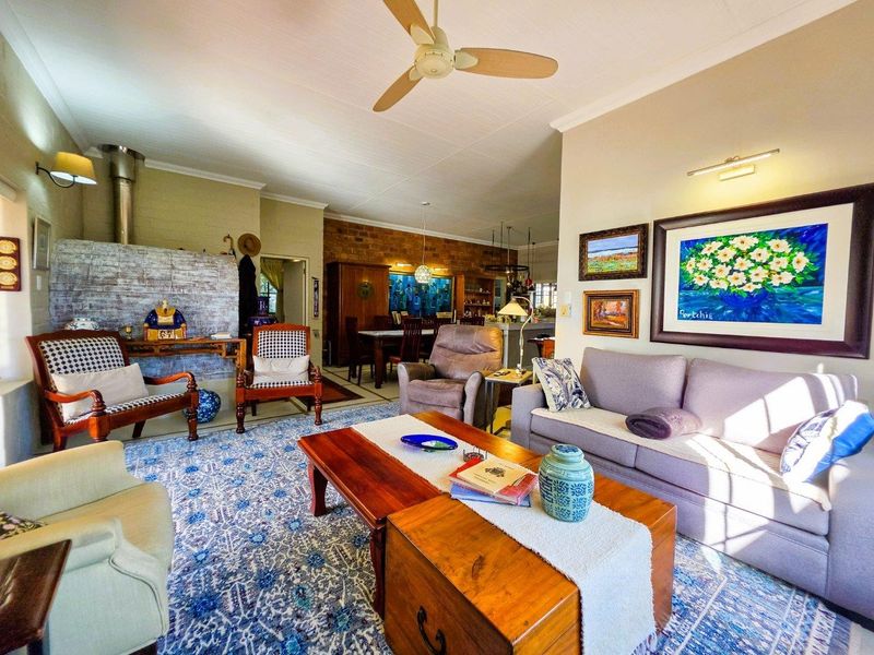 Spacious open-plan living and dining area featuring an exposed brick wall, fireplace, and ceiling fan, creating a warm and inviting atmosphere.