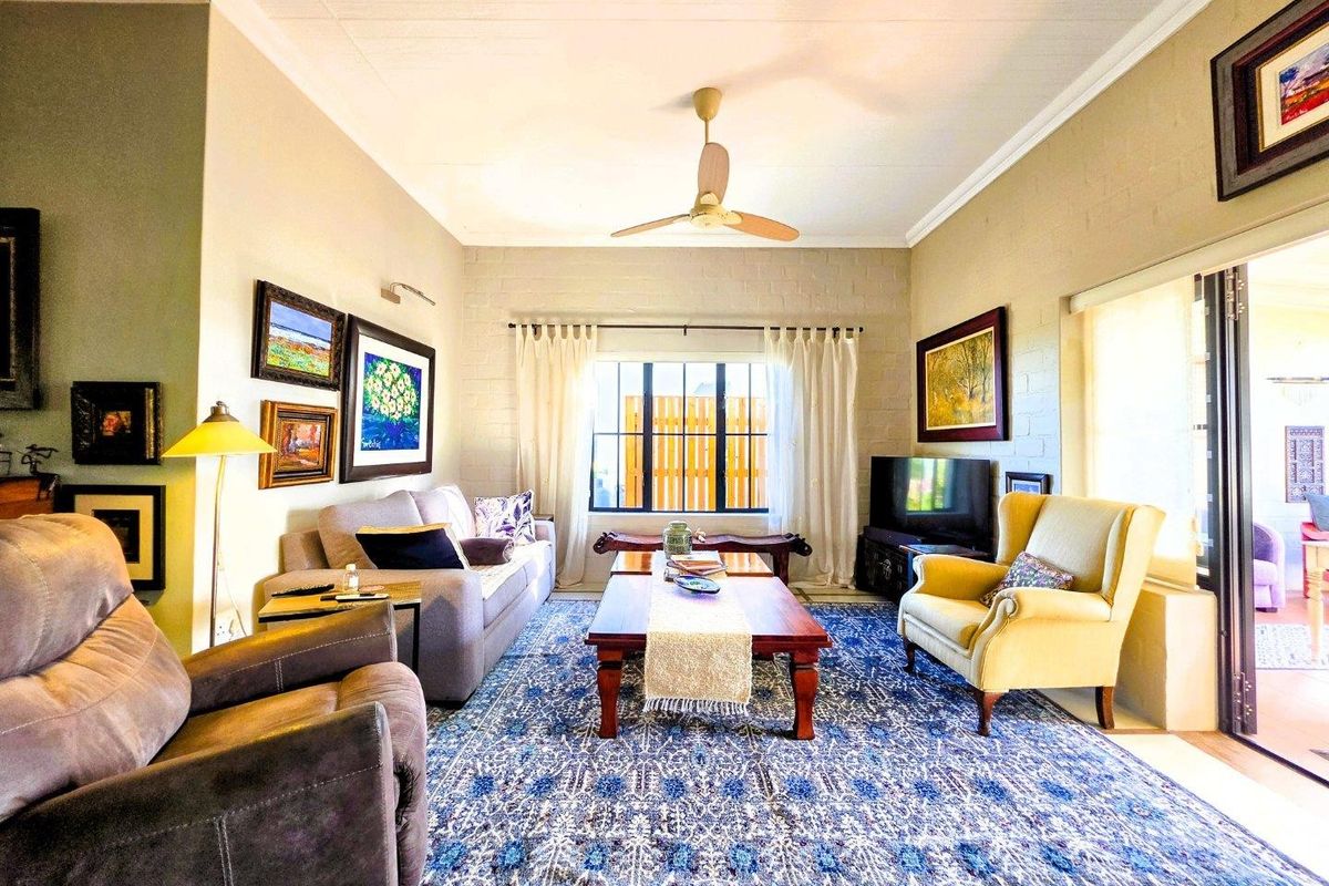 A comfortable living room featuring painted brick walls, a ceiling fan, and large sliding glass doors providing access to the outdoor area.
