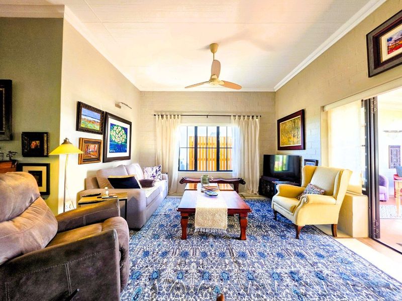 A comfortable living room featuring painted brick walls, a ceiling fan, and large sliding glass doors providing access to the outdoor area.