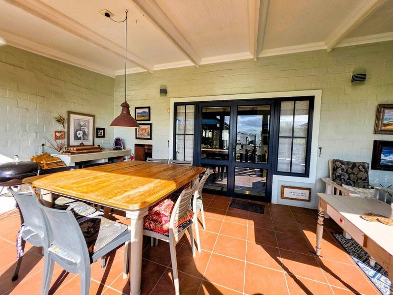 Covered patio area featuring terracotta tiling, exposed beam ceiling, and built-in masonry counter, providing a functional outdoor entertainment space.