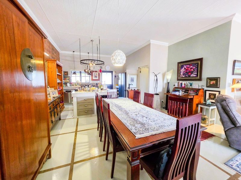 Spacious open-plan living and dining area featuring a central kitchen island, tiled flooring, and integrated cabinetry, creating a functional and connected family space.