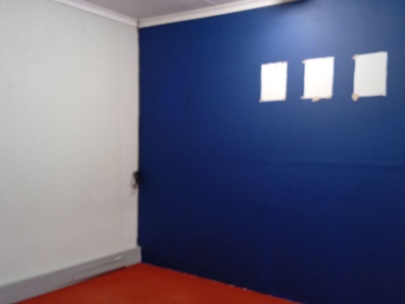 An empty office space featuring a bold blue accent wall and contrasting white wall, ready for customization or professional fit-out.
