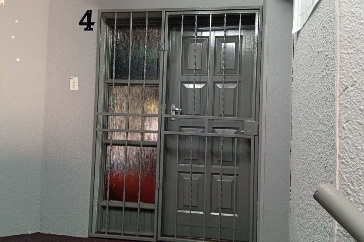 Entrance area featuring a secure metal gate and textured glass panel, providing a functional and secure access point to the unit.