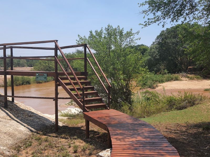 A scenic view of a river featuring a well-maintained wooden walkway and staircase providing access to the waterfront area.