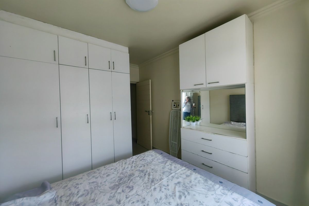 A bedroom featuring extensive white built-in cabinetry and a integrated vanity unit with a mirror, providing ample storage space.
