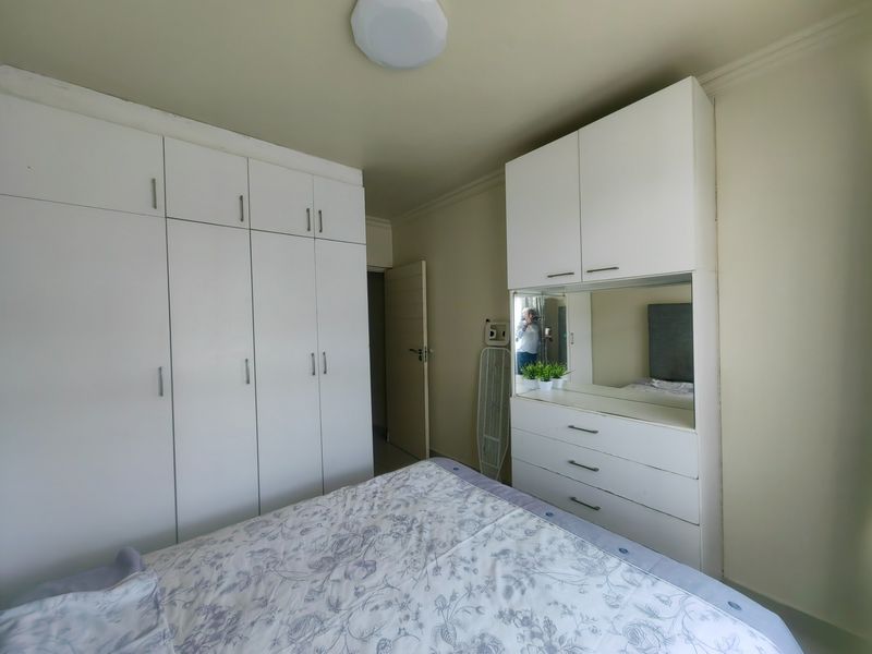 A bedroom featuring extensive white built-in cabinetry and a integrated vanity unit with a mirror, providing ample storage space.