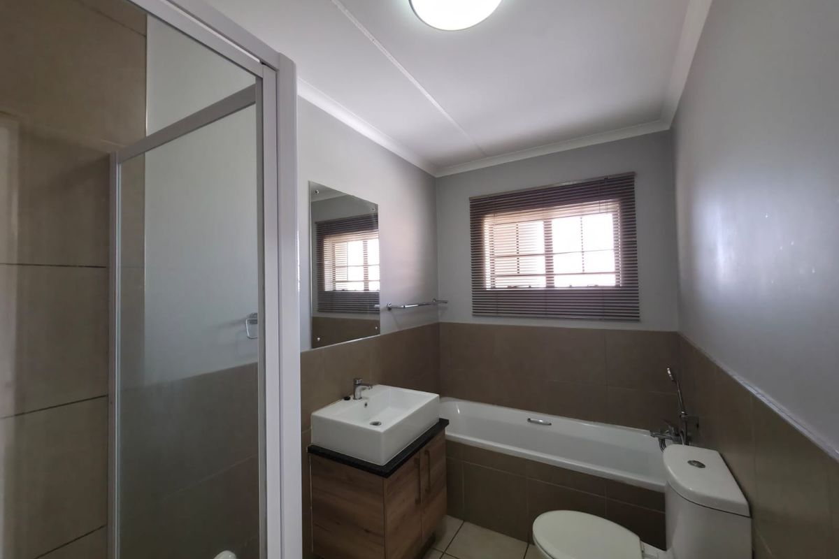 A well-maintained bathroom featuring a shower enclosure, bathtub, vanity with vessel sink, and neutral wall tiling.