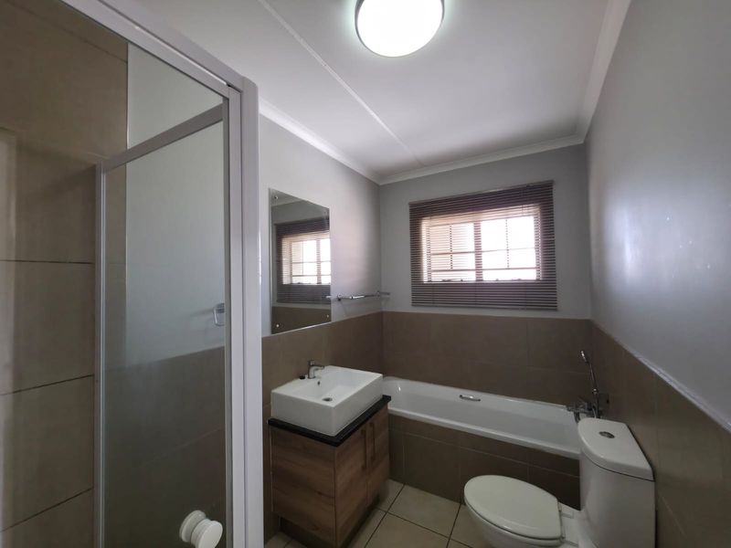 A well-maintained bathroom featuring a shower enclosure, bathtub, vanity with vessel sink, and neutral wall tiling.
