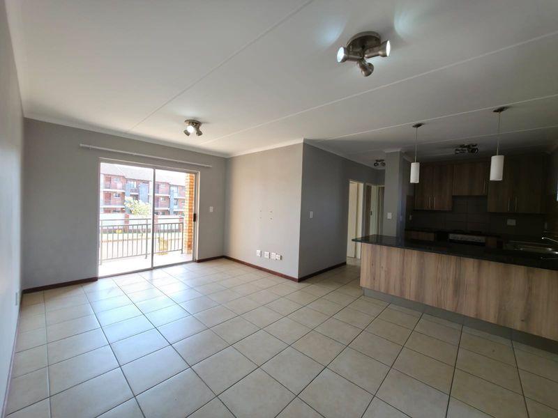Spacious open-plan living and kitchen area featuring tiled floors, modern cabinetry, granite countertops, and direct access to a private balcony.