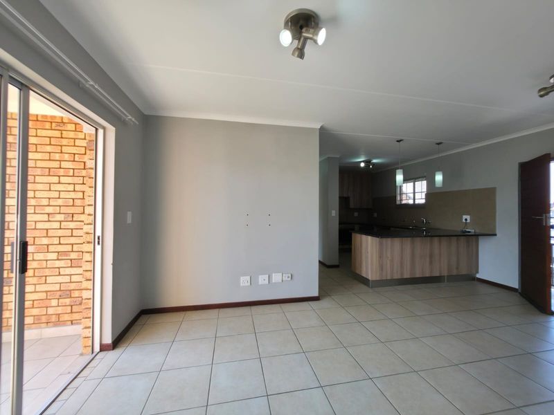 Spacious open-plan living and kitchen area featuring tiled floors, modern cabinetry, granite countertops, and direct access to a private balcony.