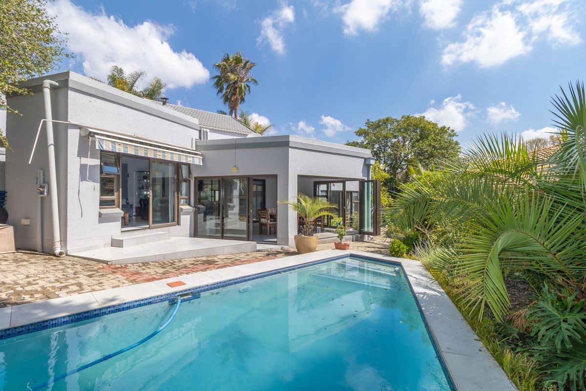 Rear exterior view featuring a swimming pool, paved patio area, and direct access to the home through sliding and bi-fold glass doors.