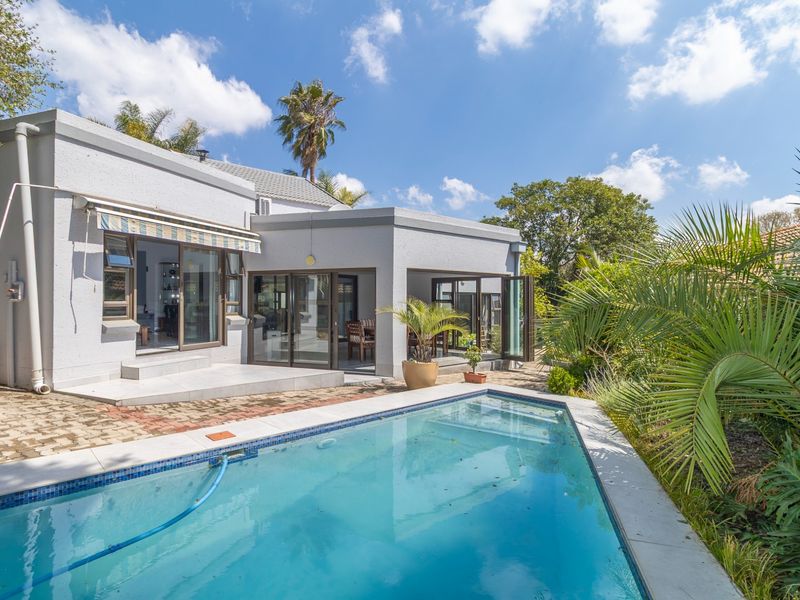 Rear exterior view featuring a swimming pool, paved patio area, and direct access to the home through sliding and bi-fold glass doors.
