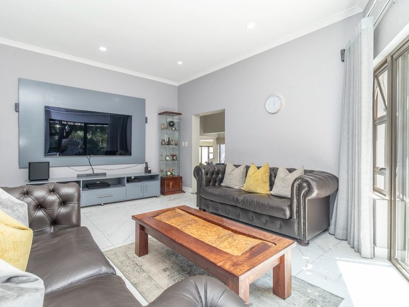 A bright and well-maintained living room featuring tiled flooring, recessed lighting, crown molding, and large sliding glass doors providing natural light.