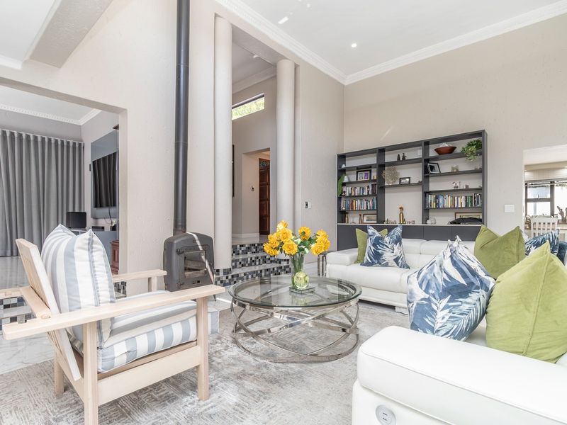Spacious living room featuring a modern freestanding fireplace, built-in shelving, elegant decorative columns, and tiled steps leading to an adjacent area.