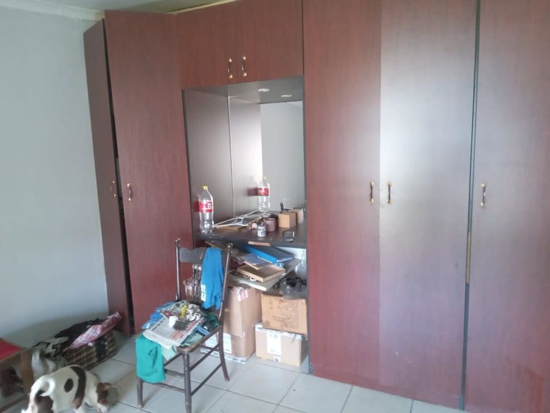 A bedroom featuring extensive built-in wooden cupboards with an integrated vanity area and tiled flooring.