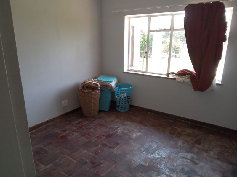 A vacant bedroom featuring original parquet flooring and a large metal-framed window, offering a blank canvas for potential renovation or interior design updates.