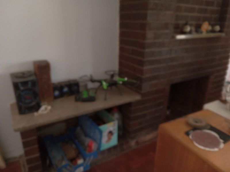 A living room area featuring a traditional brick fireplace with a built-in stone hearth.