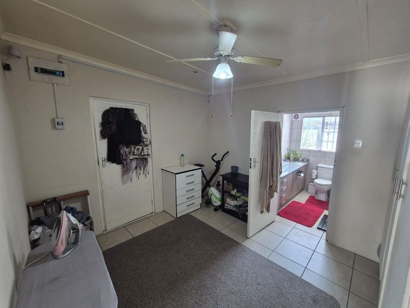 A bedroom featuring tiled flooring, a ceiling fan, and direct access to an en-suite bathroom.