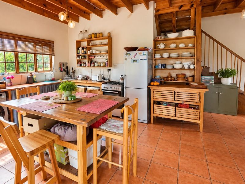 Spacious open-plan kitchen and dining area featuring exposed timber ceiling beams, terracotta flooring, and a wooden staircase leading to the upper level.