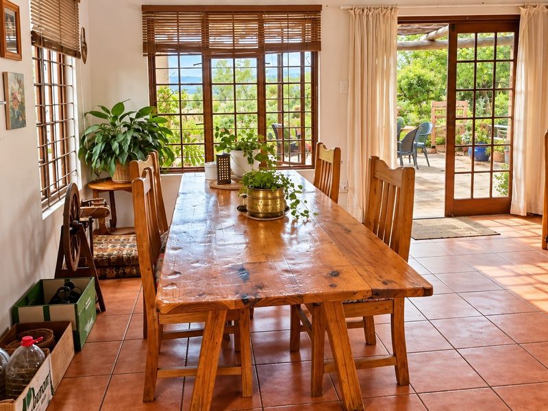 A bright dining room featuring terracotta floor tiles, wooden window frames, and direct access to an outdoor patio area through timber french doors.