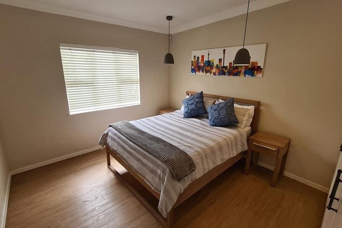 A well-maintained bedroom featuring laminate flooring, modern pendant lighting, and built-in storage, offering a clean and comfortable living space.