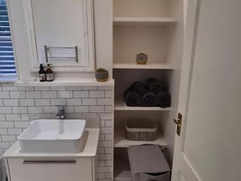 A clean, modern bathroom featuring a vessel sink on a wall-mounted vanity, subway tile backsplash, and convenient built-in shelving.
