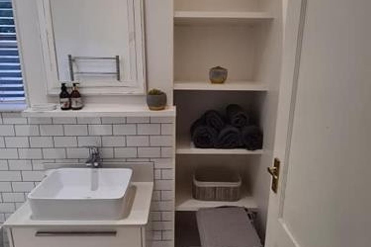 A clean, modern bathroom featuring a vessel sink on a wall-mounted vanity, subway tile backsplash, and convenient built-in shelving.