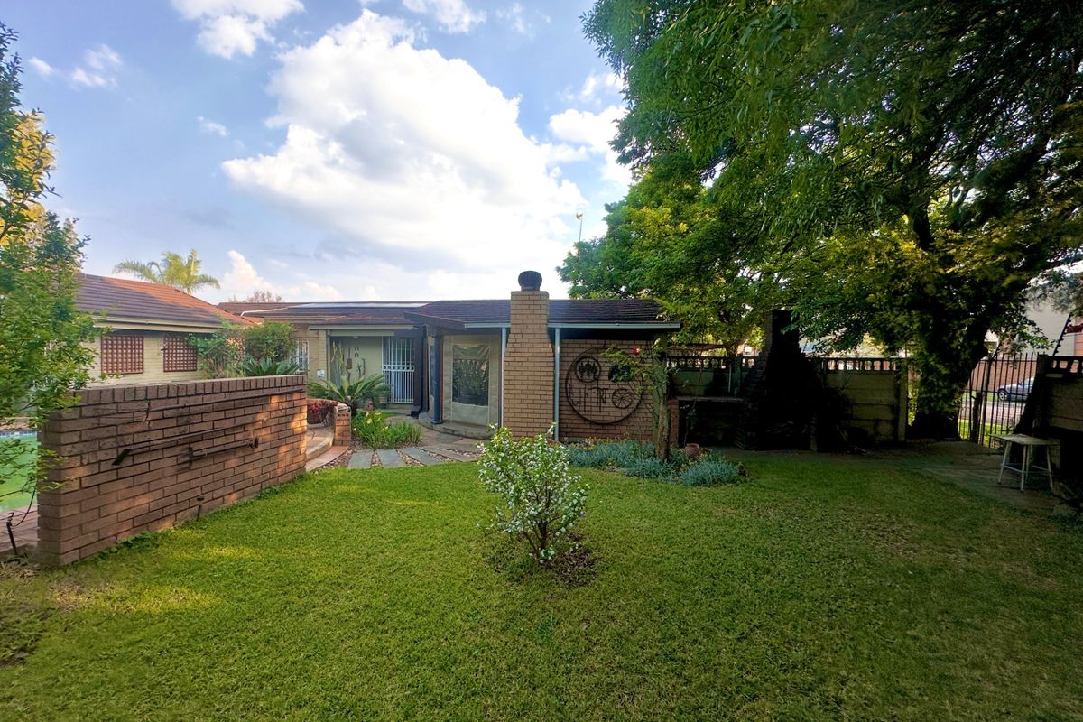A spacious rear garden featuring a brick chimney, built-in braai area, and established landscaping, providing a private outdoor entertainment space.