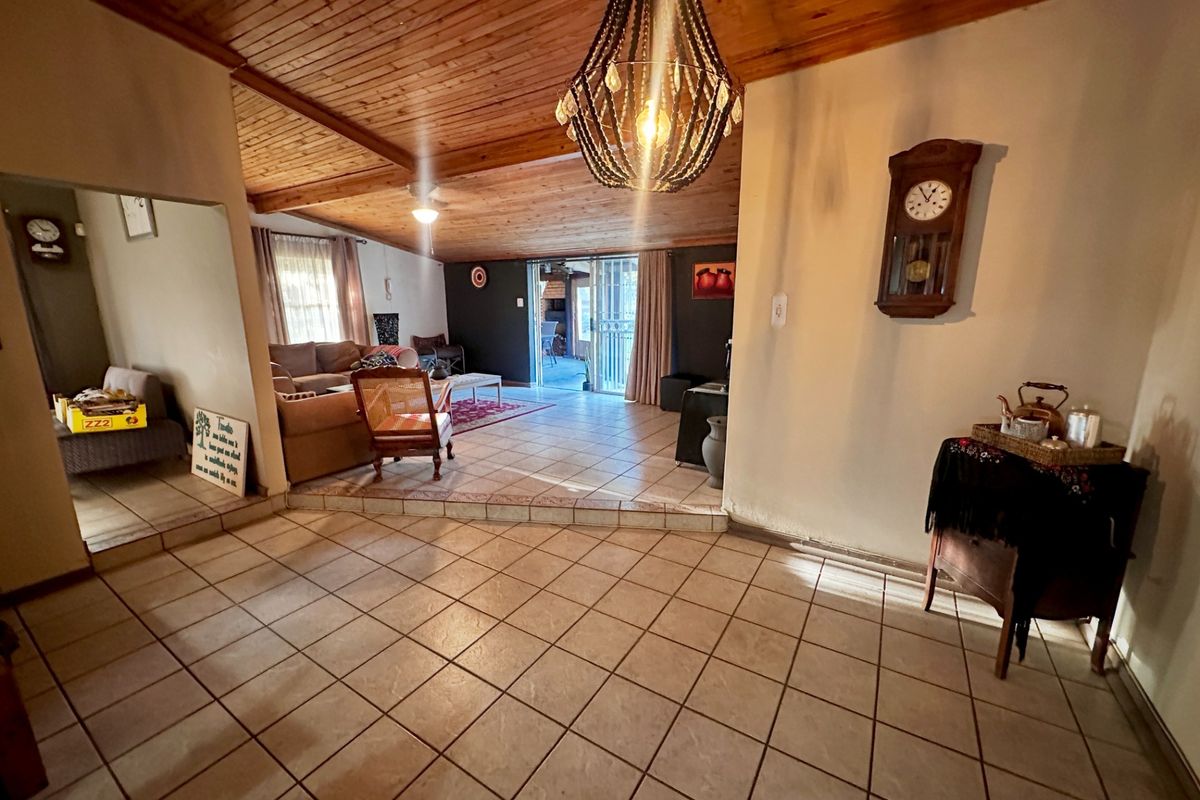 Spacious living area featuring a timber-clad ceiling, tiled flooring, and a sunken lounge space with direct access to the outdoor area.
