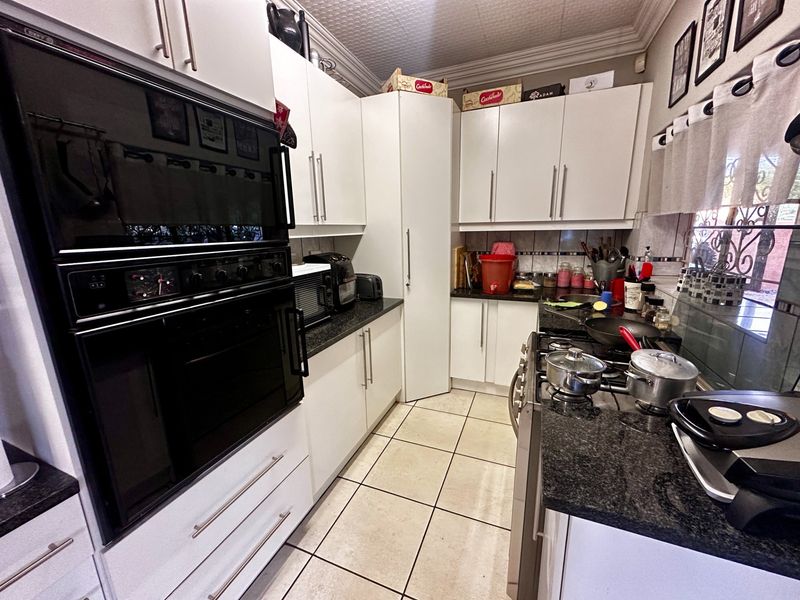 A functional kitchen featuring white cabinetry, granite countertops, a built-in oven, gas hob, and tiled flooring with a decorative ceiling finish.