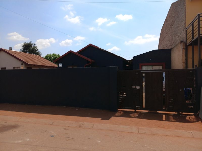 Front view of the property featuring a solid perimeter wall, secure sliding gate, and tiled roof structure.