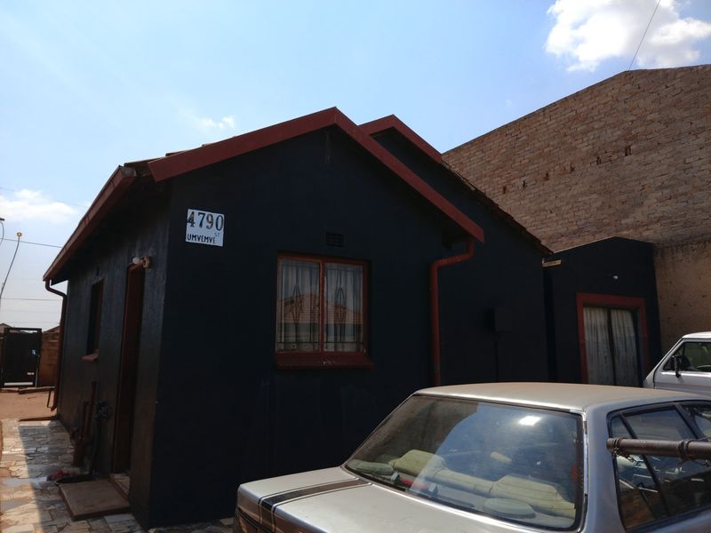 Front elevation of a residential house featuring dark painted exterior walls, a tiled roof, and security bars on the windows.
