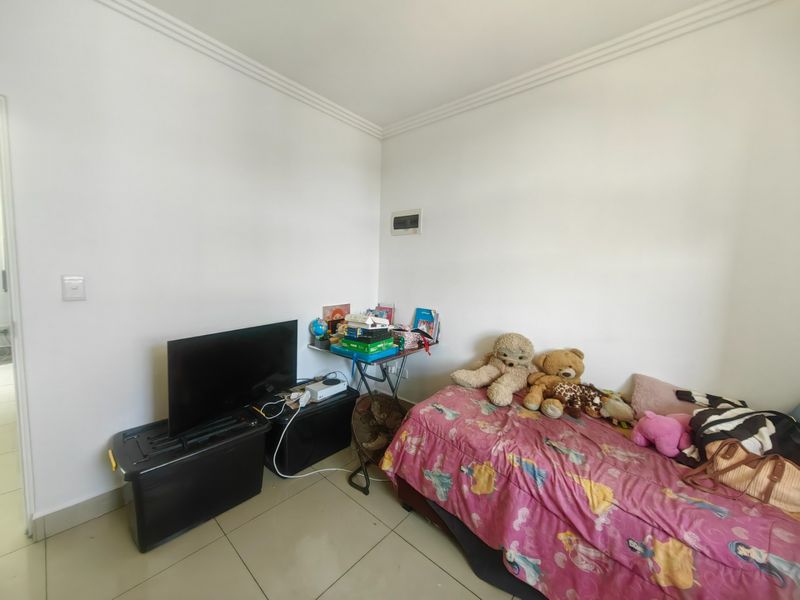 A bedroom featuring tiled flooring and decorative cove cornicing, providing a neutral base for potential interior updates.