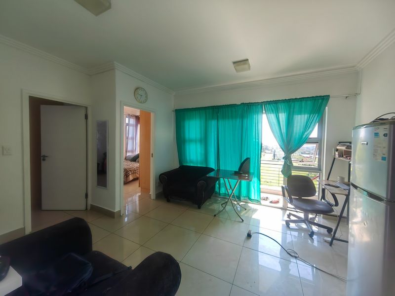 Open plan living area featuring tiled flooring and direct access to a balcony through a sliding glass door.