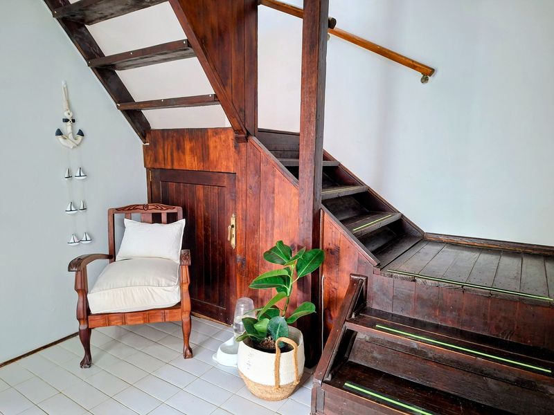 A hallway area featuring a traditional wooden staircase with integrated under-stair storage and tiled flooring.