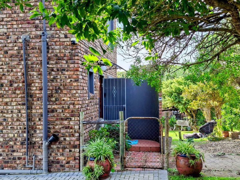A view of the rear exterior featuring face brick walls, a security gate, and a small tiled entrance area leading to the garden.