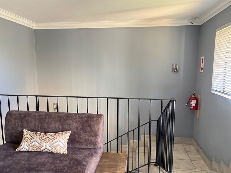 A functional hallway area featuring a metal balustrade overlooking a staircase, tiled flooring, and essential safety equipment including a wall-mounted fire extinguisher.