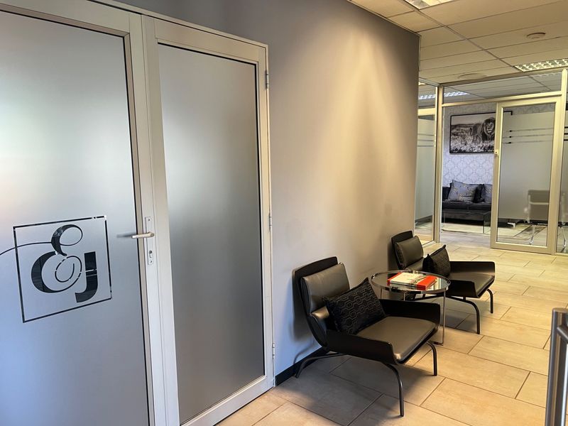A professional commercial hallway featuring frosted glass office doors, ceramic tile flooring, and a suspended ceiling system.