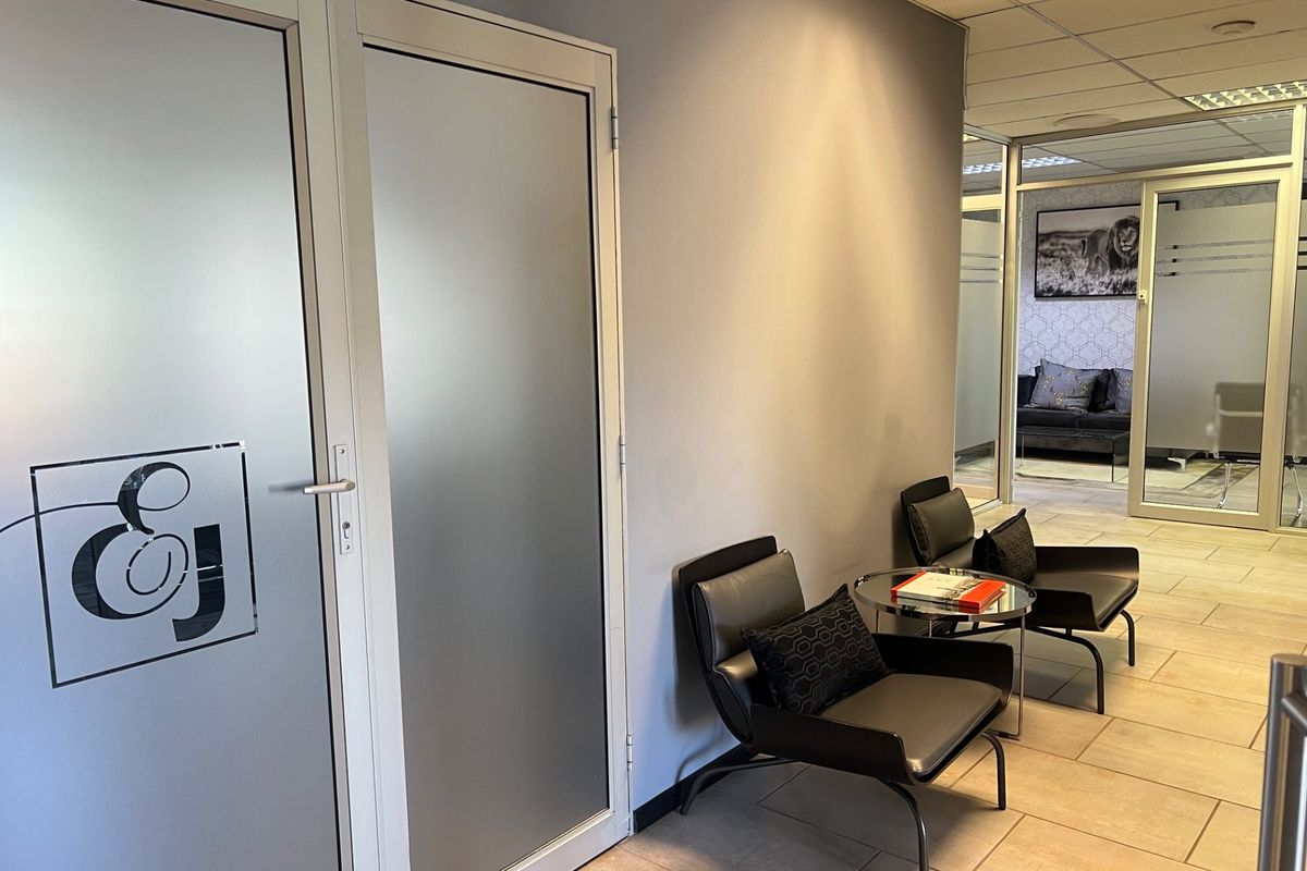 A professional commercial hallway featuring frosted glass office doors, ceramic tile flooring, and a suspended ceiling system.